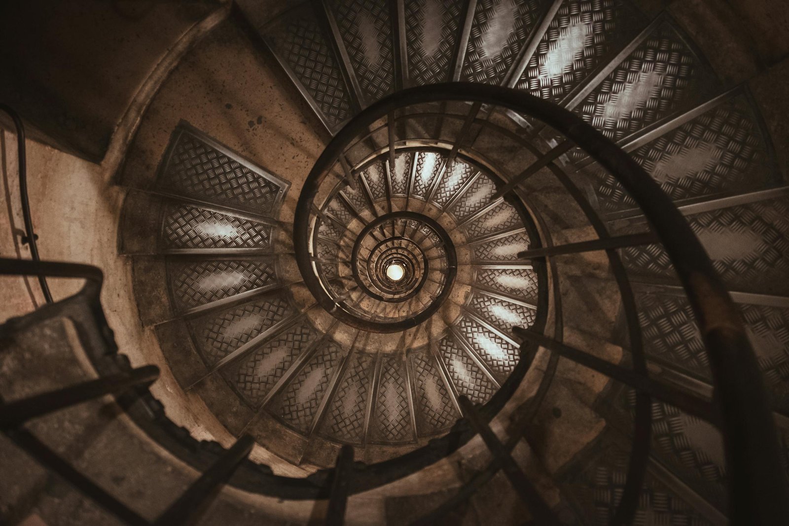 A dramatic perspective of a vintage spiral staircase inside an iconic Paris landmark.