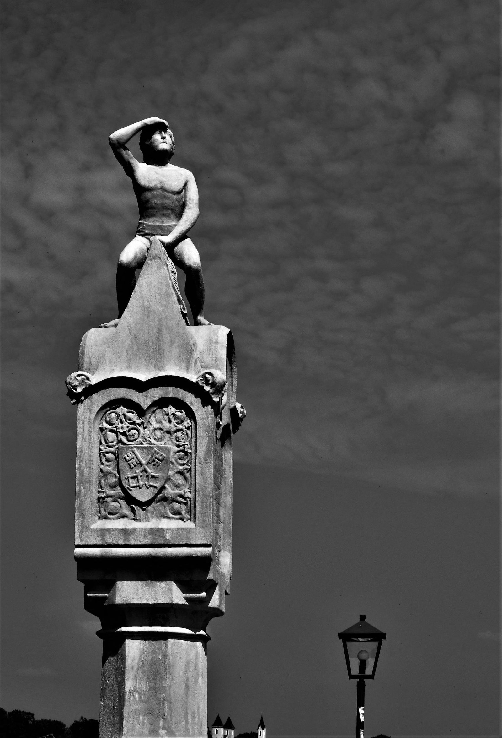 A striking black and white photo of a statue in Regensburg, set against a textured sky.