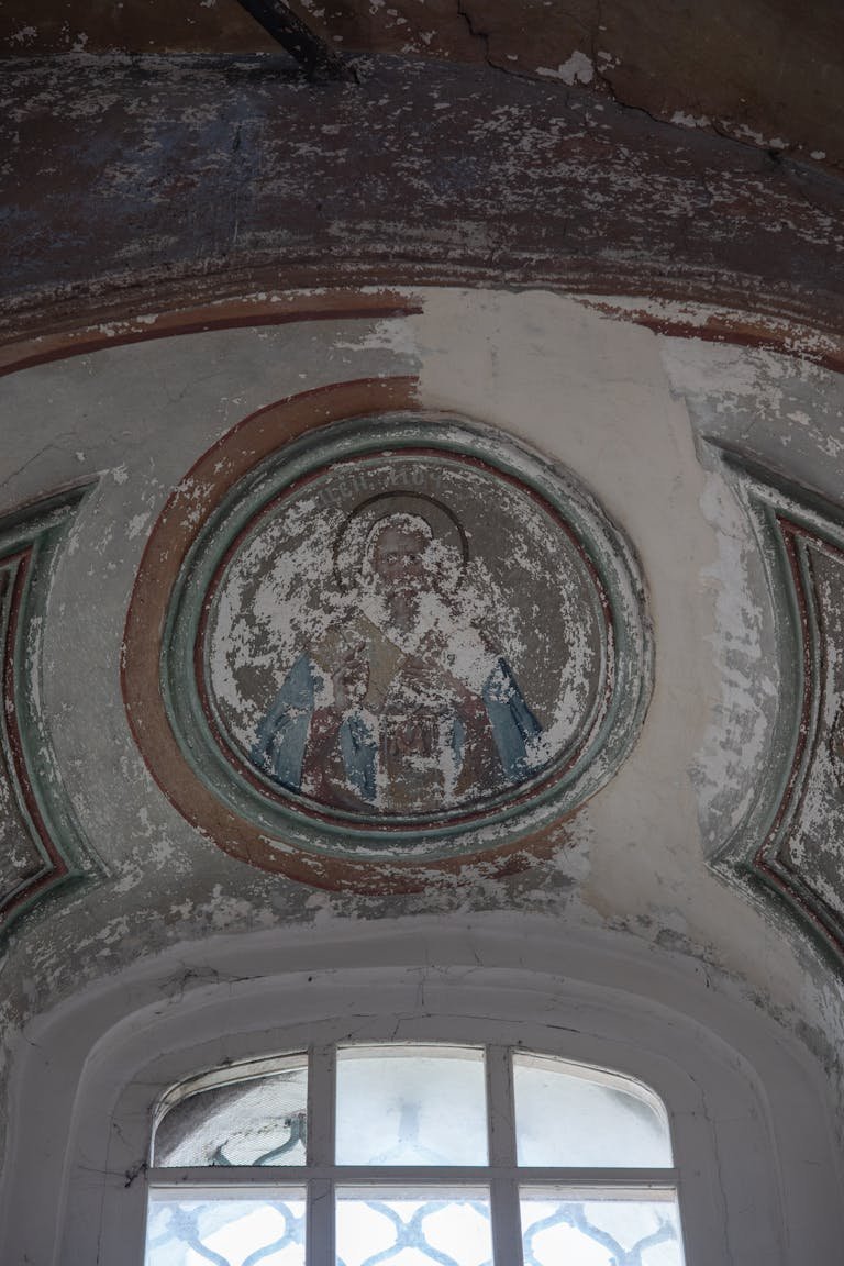 Aged fresco on a church ceiling, showcasing weathered sacred art.