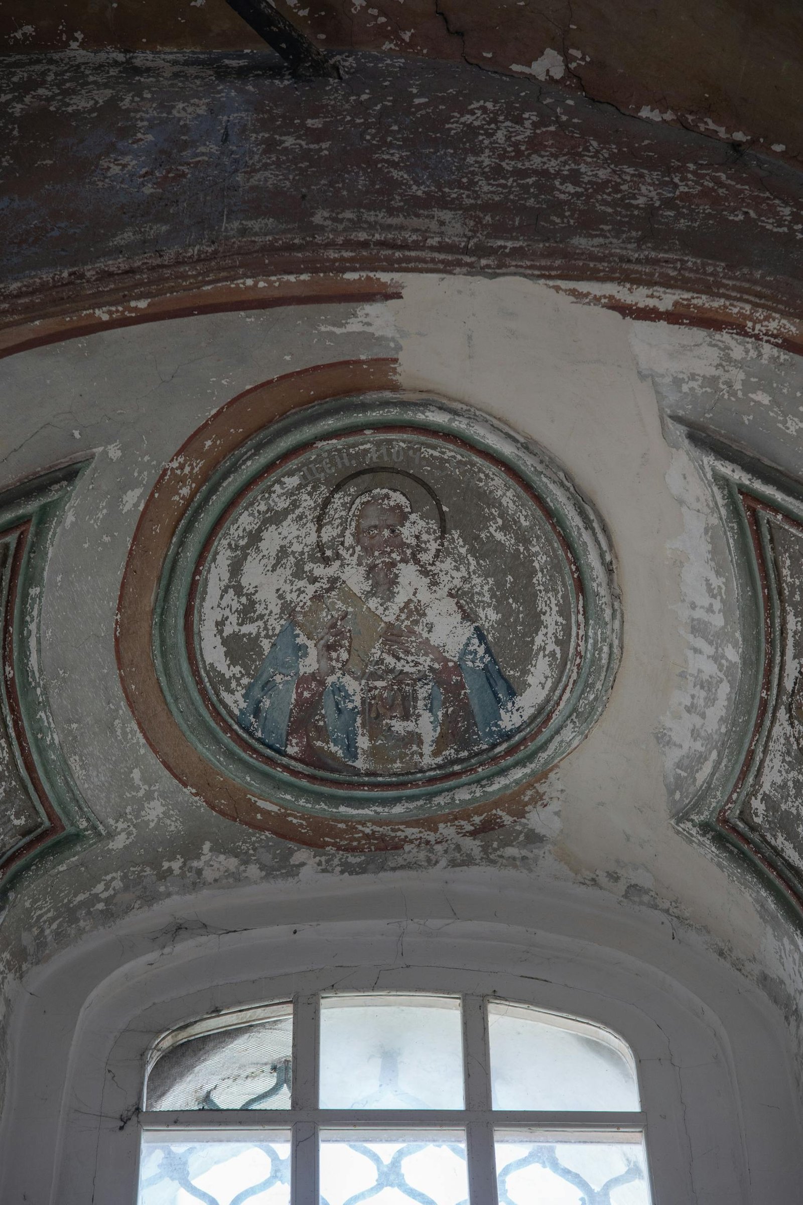 Aged fresco on a church ceiling, showcasing weathered sacred art.