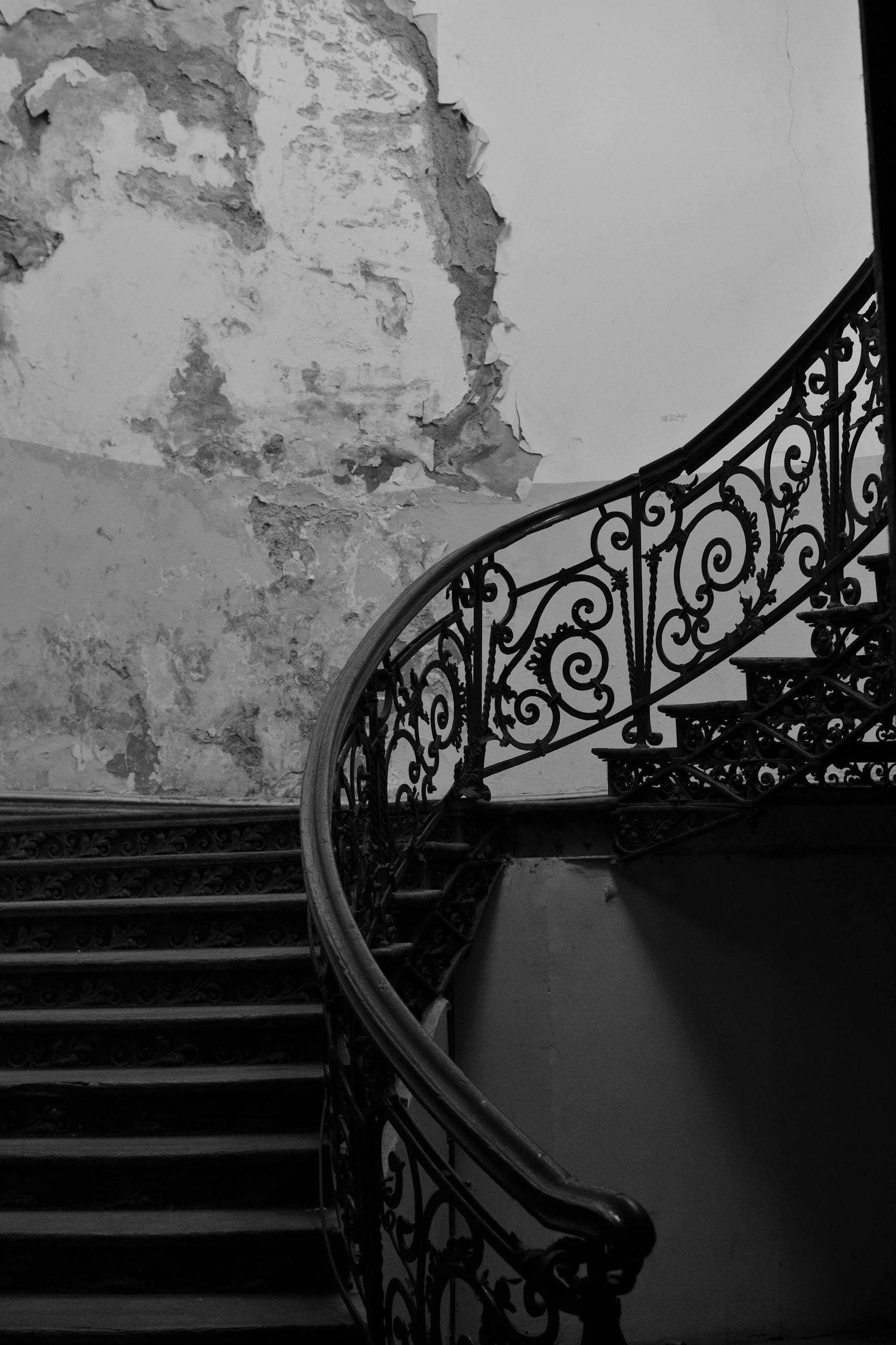 Black and white image of a vintage wrought iron staircase in an old residential building.