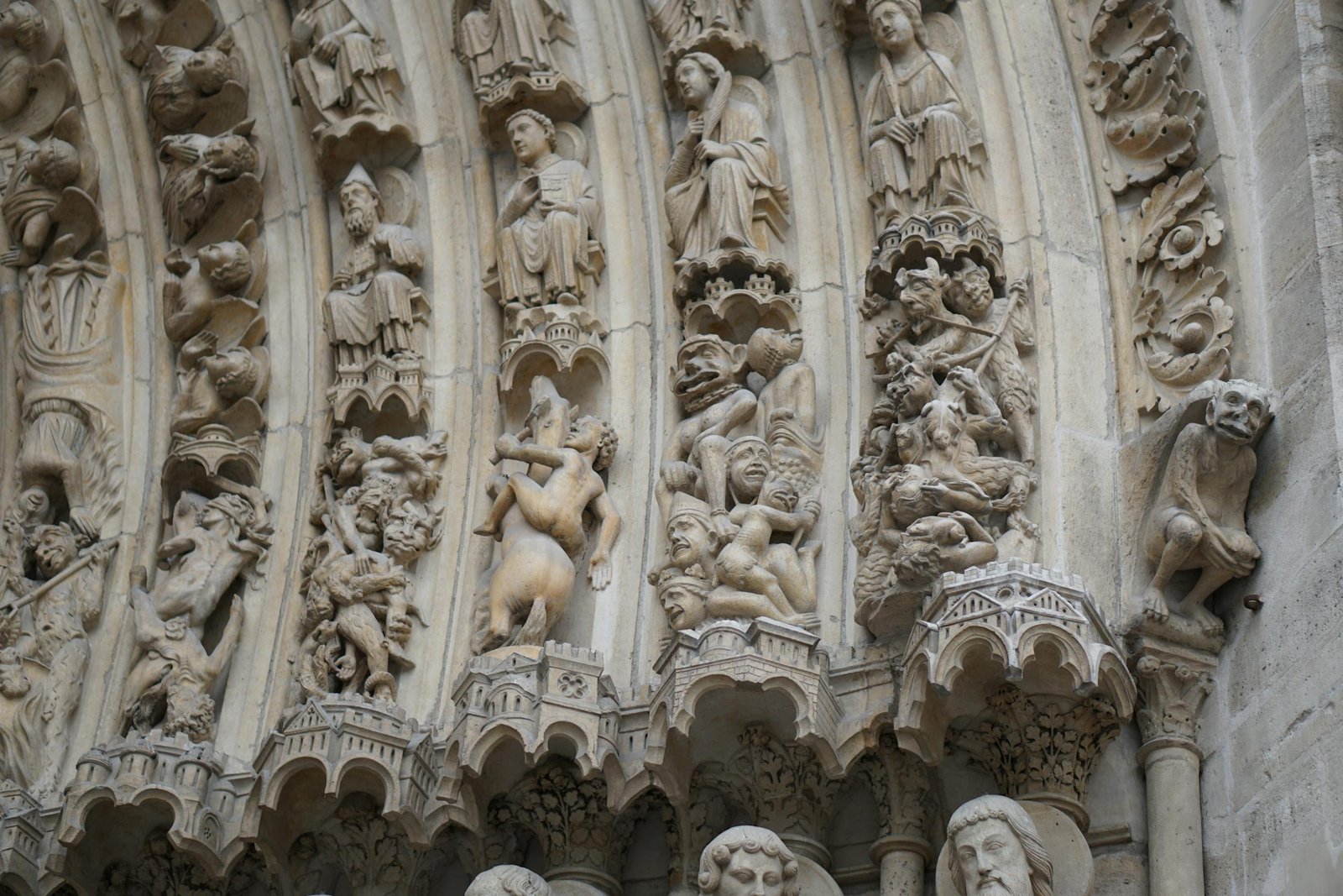 Close-up of detailed bas relief sculptures on a Gothic cathedral exterior, showcasing religious art.