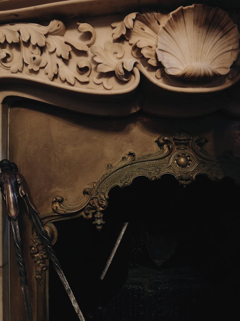 Detailed close-up of an ornate antique fireplace with intricate carvings and brass elements.