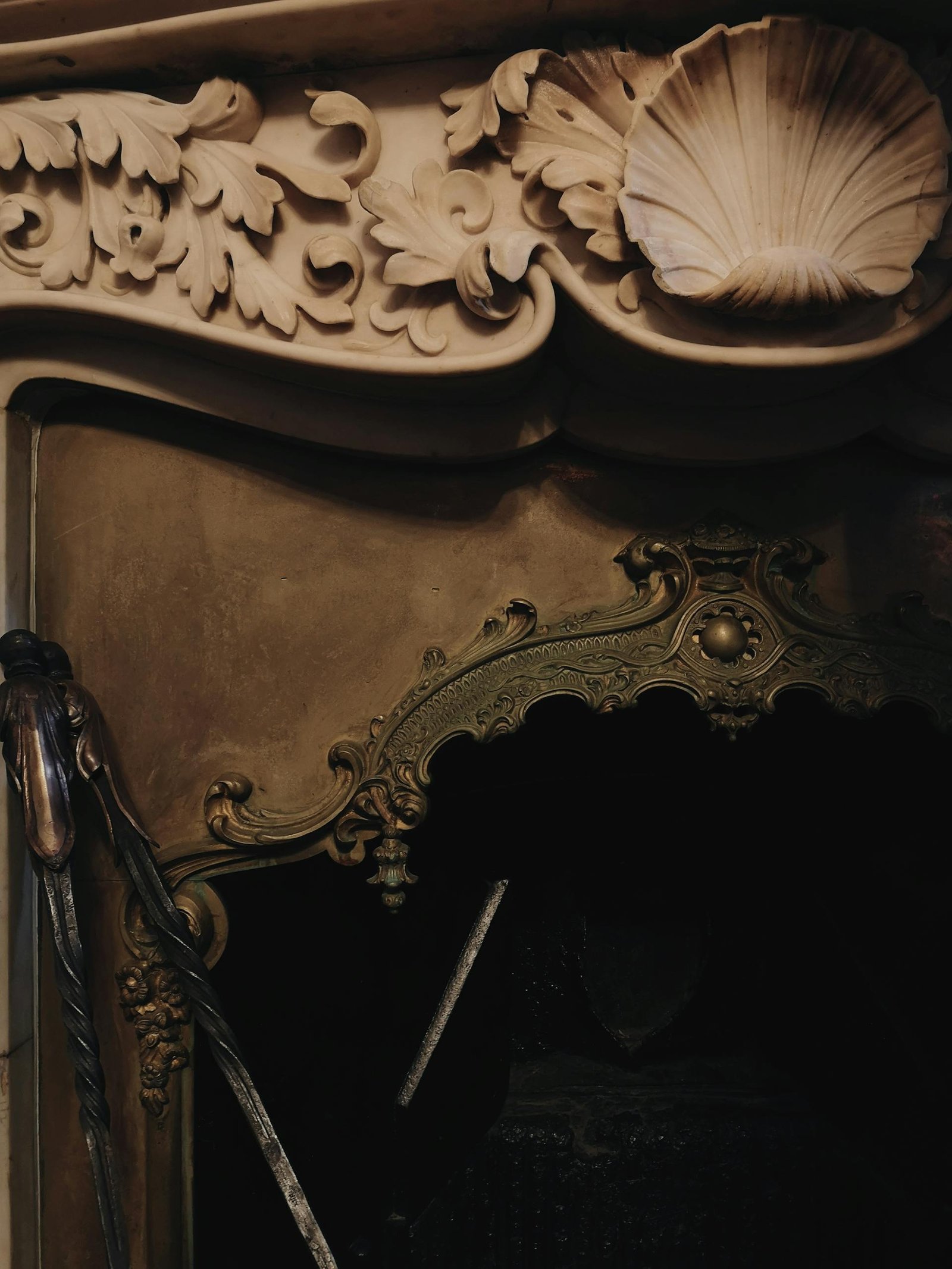 Detailed close-up of an ornate antique fireplace with intricate carvings and brass elements.