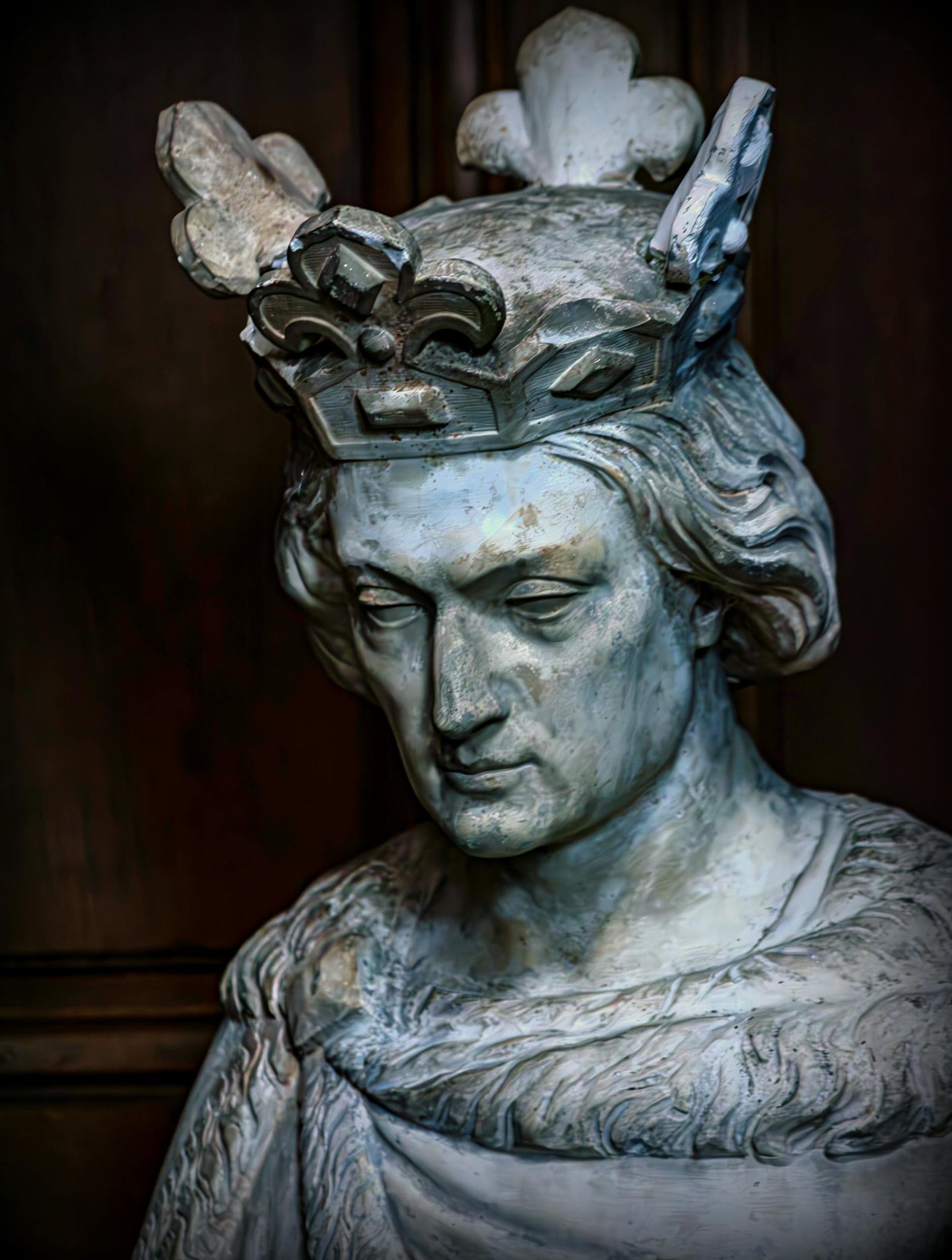 Detailed sculpture of a medieval king adorned with an ornate crown on display indoors.