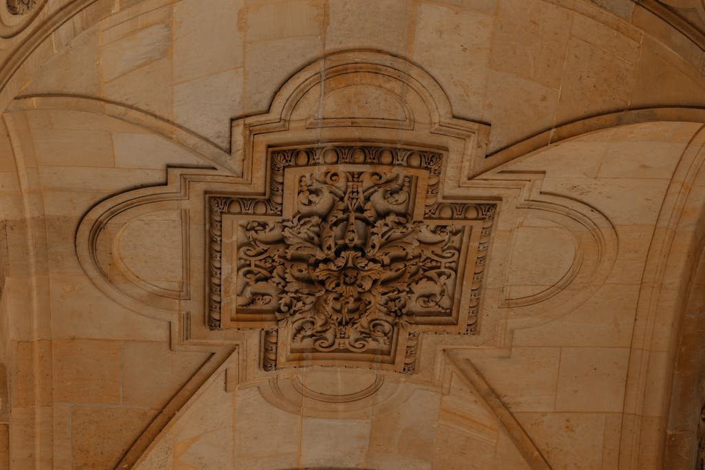 Detailed stone ceiling decoration in a historic Paris building showcasing intricate craftsmanship.