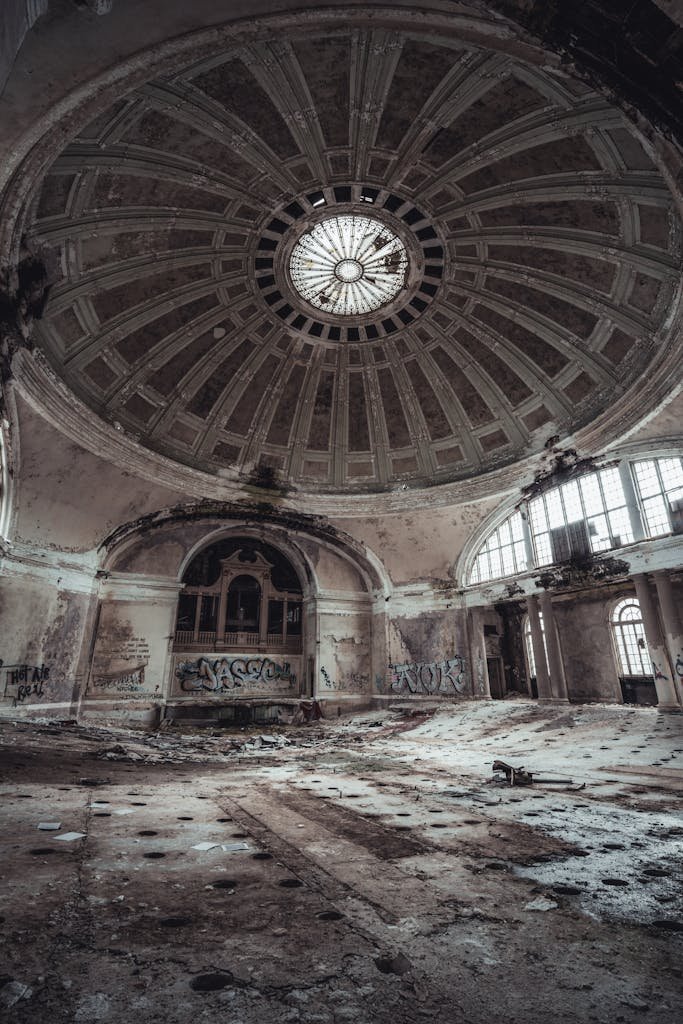 Explore an abandoned building with a grand dome ceiling and graffiti on the walls.