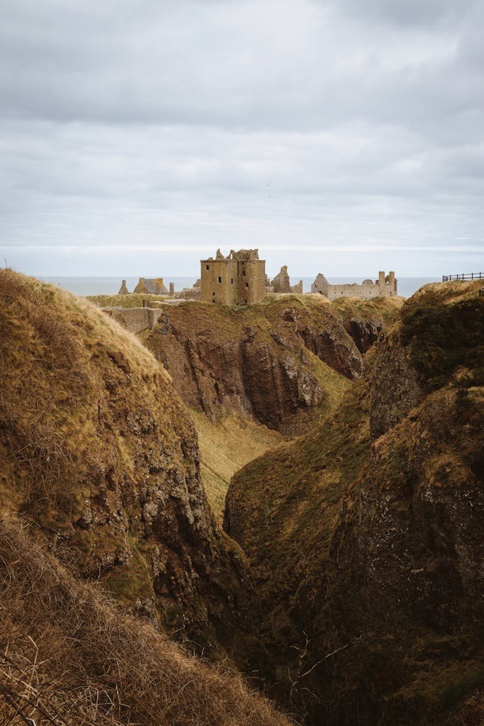 Scenic view of Dunnottar Castle perched on cliffs, surrounded by rugged landscape in Scotland.